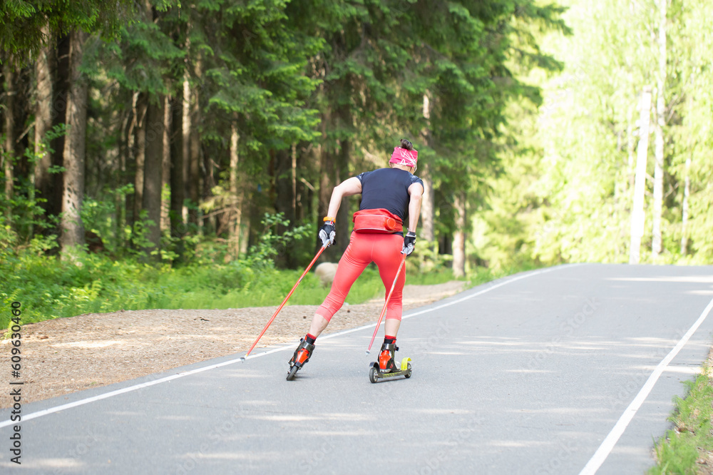 Fototapeta premium Roller skis.A woman runs in a summer park on roller skis.Cross country skilling.