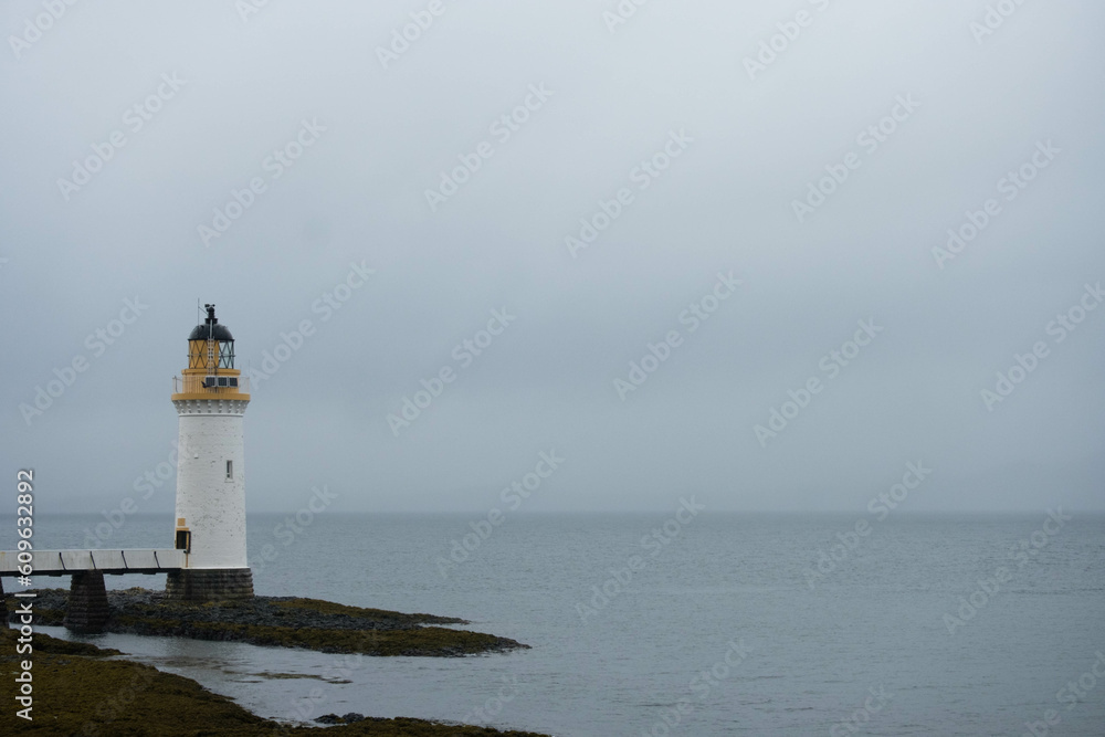 A lighthouse overlooking the sea by a scottish island