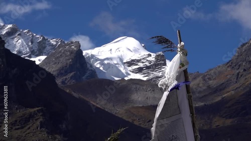 tibetan prayer flags on high posts with himalaya mountain, 2023
 snow covered peaks in background and clear blue sky, Slow motion, 2023
