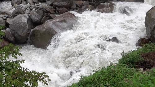 White water river flowing fiercly between boulders and vegetation
Slow motion shot if raging river, Nepal, 2023
 photo