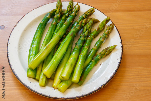 Green boiled asparagus in a plate on a wooden table