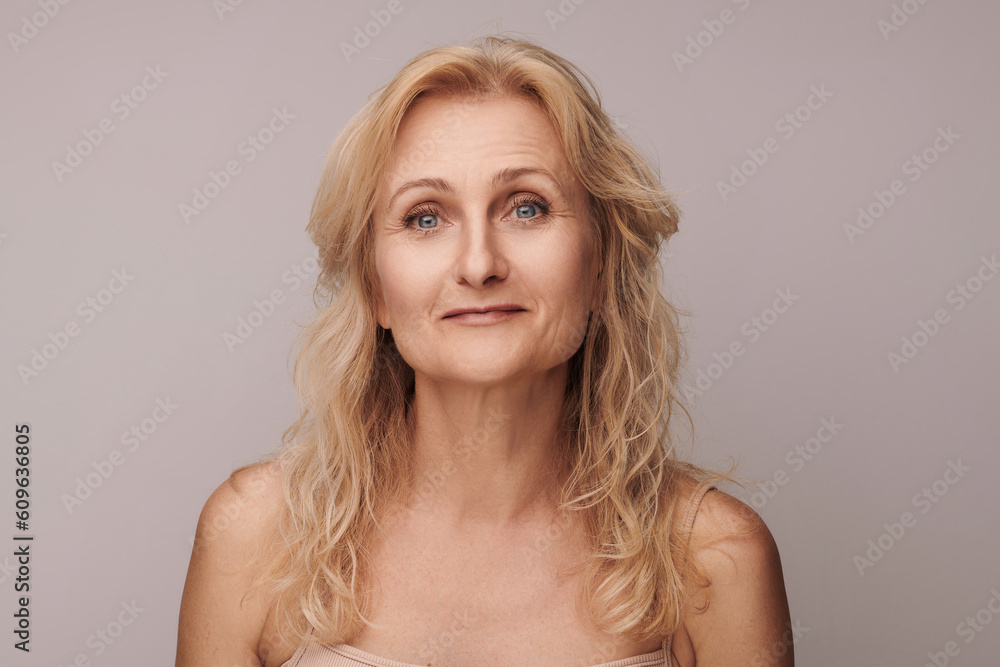Beautiful blond middle aged woman smiling face looking at camera portrait. Elegant mature lady no makeup 50 years old close-up isolated on white studio. Women's health, cosmetology, skin care concept Beautiful blond middle aged woman smiling face looking at camera portrait. Elegant mature lady no makeup 50 years old close-up isolated on white studio. Women's health, cosmetology, skin care concept