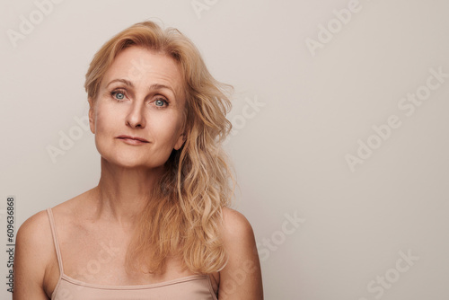 Beautiful blond middle aged woman smiling face looking at camera portrait. Elegant mature lady no makeup 50 years old close-up isolated on white studio. Women's health, cosmetology, skin care concept