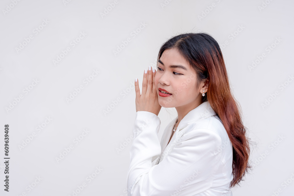 An intrigued young woman gesturing with hand on ear her and listening carefully. Isolated on a white background. An intrigued young woman gesturing with hand on ear her and listening carefully. Isolated on a white background.
