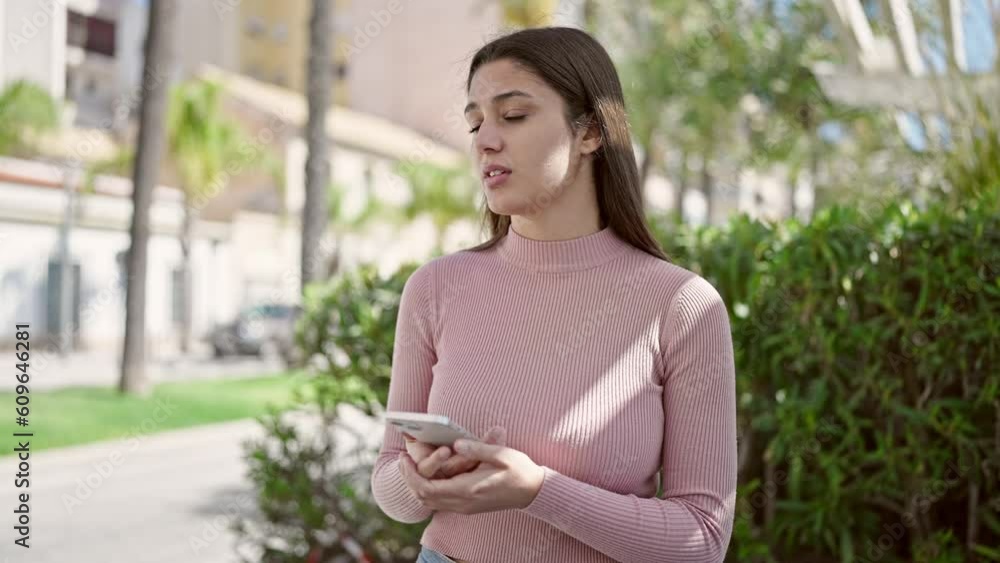 Young beautiful hispanic woman using smartphone with serious expression at park Young beautiful hispanic woman using smartphone with serious expression at park