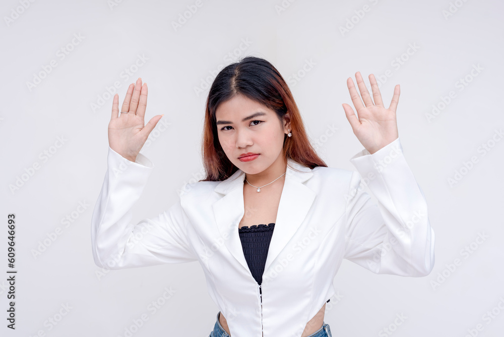 A scared and helpless young woman with both arms raised in surrender. Isolated on a white background. A scared and helpless young woman with both arms raised in surrender. Isolated on a white background.