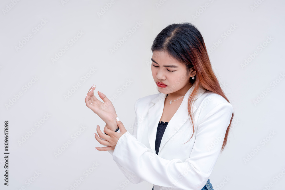 A distressed young woman looking at her wrist while rubbing it in pain. Isolated on a white background. A distressed young woman looking at her wrist while rubbing it in pain. Isolated on a white background.