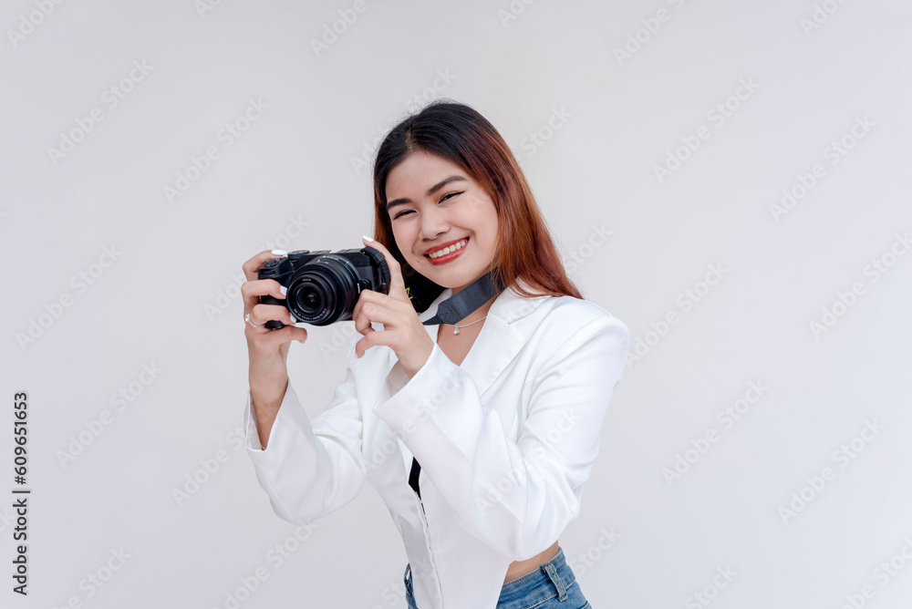 A happy young woman holding a camera in eye-level while taking pictures. Isolated on a white background. A happy young woman holding a camera in eye-level while taking pictures. Isolated on a white background.
