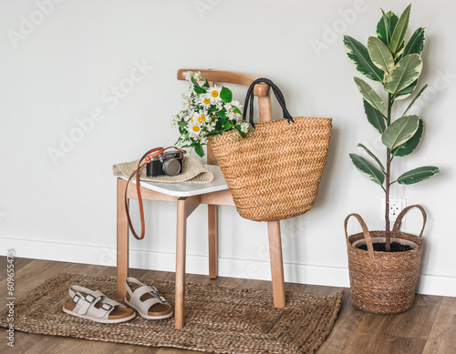 The interior of the corridor is a straw basket with flowers and a camera on a chair, sandals on a jute rug, a basket with a ficus. Cozy atmosphere photo