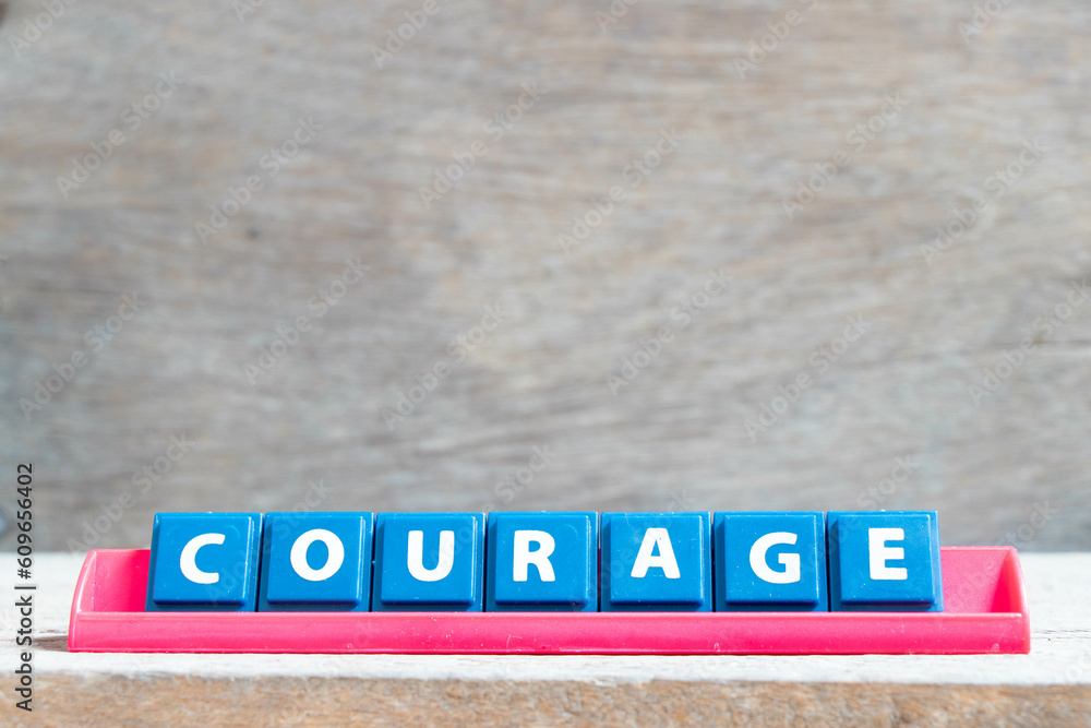 Obraz premium Tile alphabet letter with word courage in red color rack on wood background