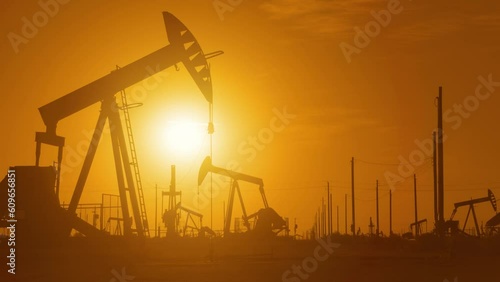 The sun rises behind a large oil field in California.