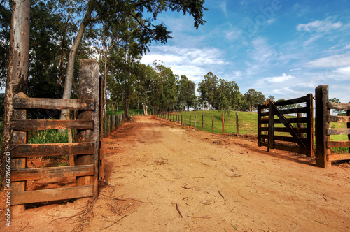 Estrada rural de terra com porteira aberta para a fazenda  photo
