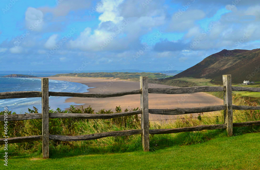 Rhossili beach in Wales, UK with a wooden fence and a lot of clouds