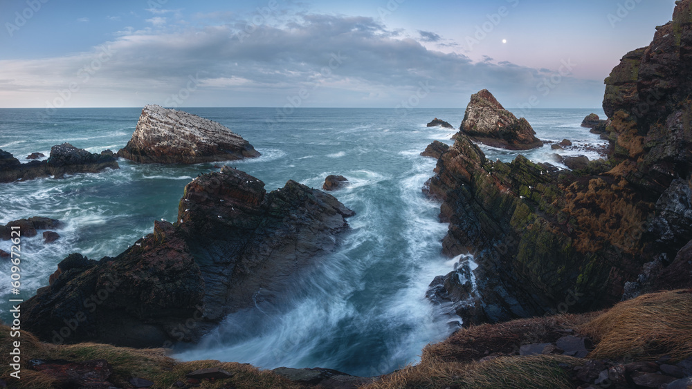Obraz premium Amazing panorama of the sea cliffs on the northern Scottish coast and rough seas. Famous rock formation on the Moray Coast, Scottish Highlands, Scotland