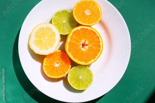 citrus mix in a plate on a green background. orange lemon and lime on a green background. mix citrus fruits.