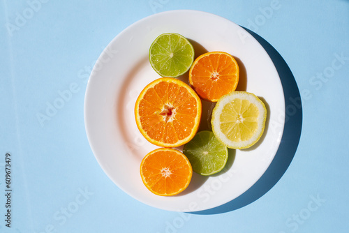 citrus mix in a plate on a blue background. Orange lemon and lime halves on a blue background. Assorted citrus fruits.