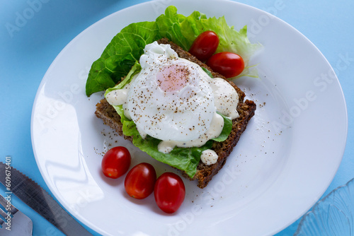 poached eggs on a blue background. delicious breakfast sandwich with salad and egg. Delicious breakfast on bright blue background