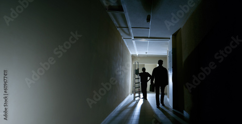 Workers in dark corridor. M...