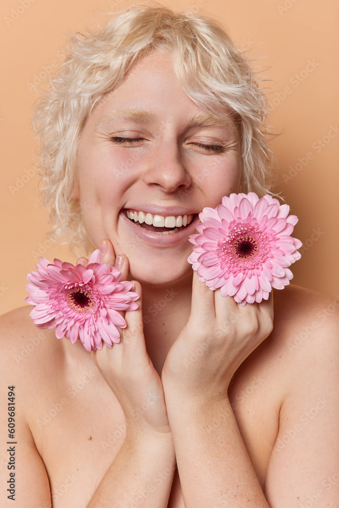 Shirtless glad woman has gentle smile and healthy skin holds pink