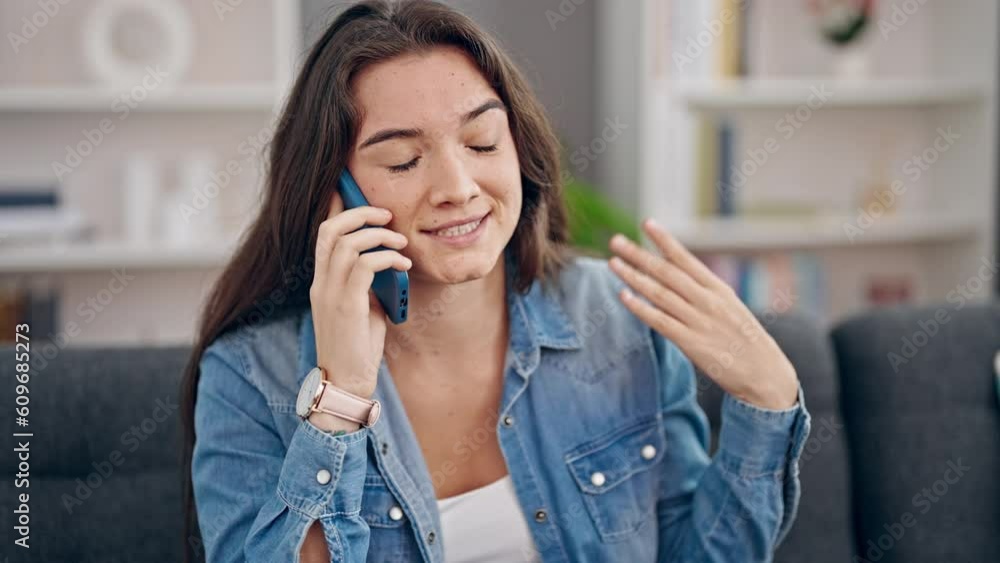 Young beautiful hispanic woman speaking on the phone sitting on sofa at home Young beautiful hispanic woman speaking on the phone sitting on sofa at home