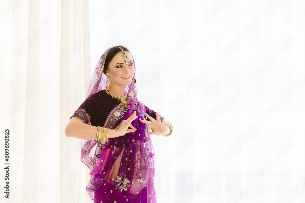 Pregnant woman in purple sari. mehendi. Indian painting on woman's hands and pregnant belly with henna tattoo on white room background