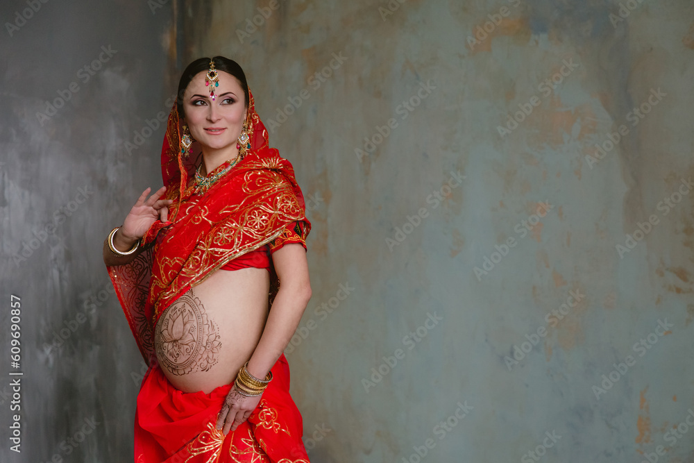 Premium Photo  Studio portrait of a happy pregnant woman in indian sari, a  pregnant belly painted with henna