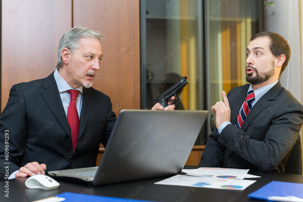 Businessman pointing his gun to a colleague's head Businessman pointing his gun to a colleague's head