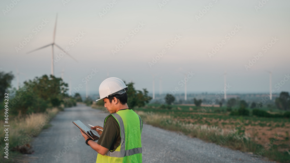 Service engineers checking system of windmill with tablet. Wind turbines generate electricity. Clean and Renewable energy concept. Service engineers checking system of windmill with tablet. Wind turbines generate electricity. Clean and Renewable energy concept.