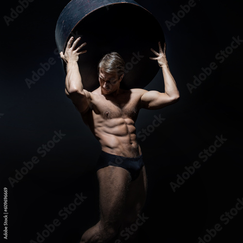 An athlete like an Atlantean, holds weight on his shoulders, a muscular athlete, the body of an ancient hero photo