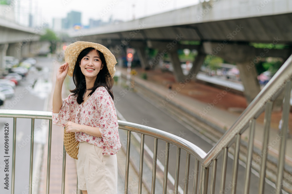 young asian woman traveler with weaving basket happy smiling standing on overpass with railway background. Journey trip lifestyle, world travel explorer or Asia summer tourism concept. young asian woman traveler with weaving basket happy smiling standing on overpass with railway background. Journey trip lifestyle, world travel explorer or Asia summer tourism concept.