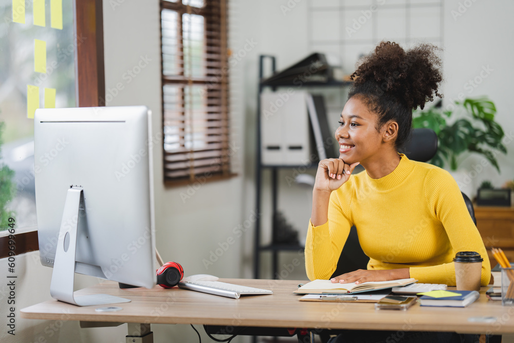 Young African American freelancer working on computer in home office. Female college student. Young African American freelancer working on computer in home office. Female college student.