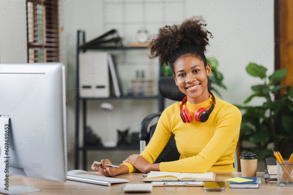 Young African American freelancer working on computer in home office. Female college student. Young African American freelancer working on computer in home office. Female college student.