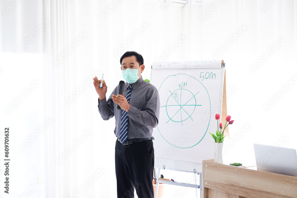 Senior Asian Lecturer is wearing mass for prevention Covid-19 virus and teaching business and stock market topics for business people in the economics class at meeting or seminar room Senior Asian Lecturer is wearing mass for prevention Covid-19 virus and teaching business and stock market topics for business people in the economics class at meeting or seminar room