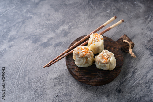 Chinese steamed dumplings or Dim Sum in bamboo steamer on dark abstract background
