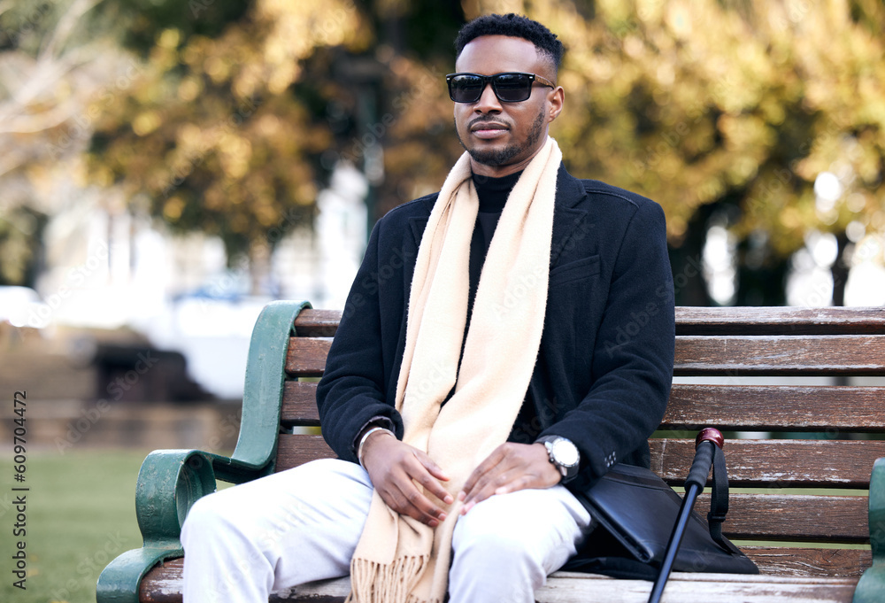 Fototapeta premium Blind black man, park bench and relax with sunglasses, walking stick or outdoor by trees, peace or thinking. African guy, vintage fashion and young person with disability, glasses or travel in nature