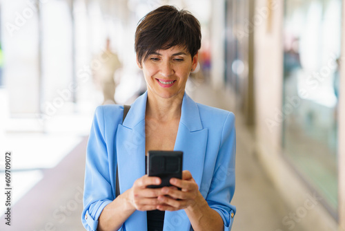 Positive mature woman surfing smartphone on street © javiindy