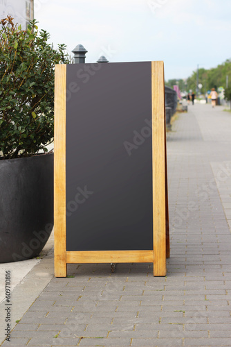 Empty black sandwich chalkboard menu board stand on a street.