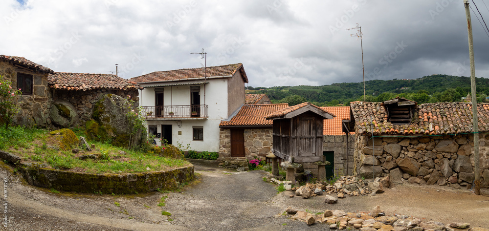 View of a street in the village of Vilanova dos Infantes in Orense, province of Galicia, with old houses, mountains in the background and cloudy sky, in summer of 2021. Spain