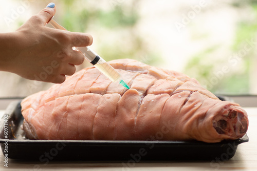 Obraz na plátně Chef Injecting brine into pork leg