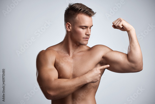 Fototapete Man, bodybuilder and pointing to bicep in studio, background and exercise for muscular power