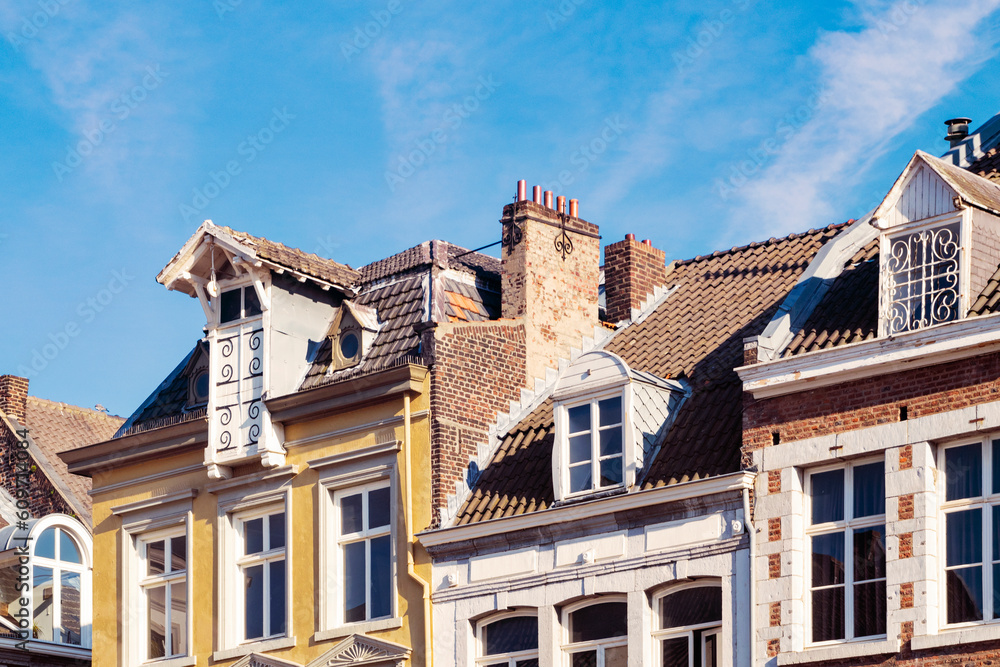 Eclectic old roofs featuring architectural details of windows and attics at sunset in May in the city of Maastricht, Netherlands. Vintage travel background. Eclectic old roofs featuring architectural details of windows and attics at sunset in May in the city of Maastricht, Netherlands. Vintage travel background.