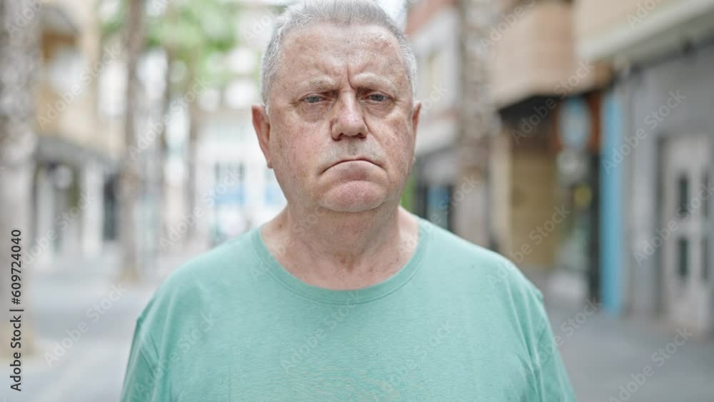 Middle age grey-haired man standing with serious expression at street Middle age grey-haired man standing with serious expression at street