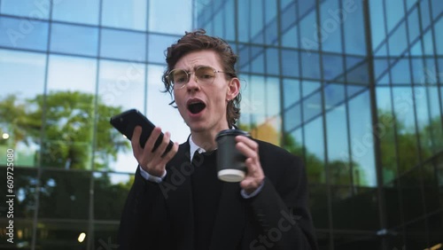 Mad man yelling on telephone standing near company office close up Angry bearded businessman talking emotionally on smartphone. Nervous man disappointed of business results screaming in phone dynamic.