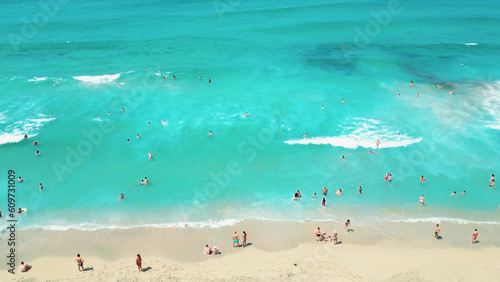 Aerial View of Turquoise Waters, Colorful Umbrellas, and Azure Sea, White Waves Along the Sandy Beaches 