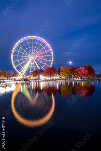 La Grande Roue de Montreal at night reflecting in the Saint Lawrence river with its lights on
