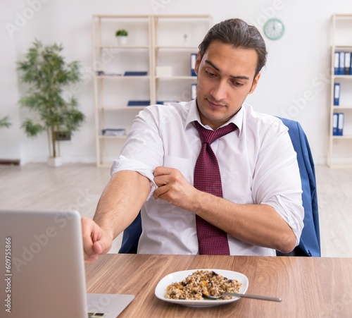 Hungry male employee eating buckwheat during break