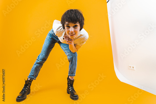 Full shot of a young smiling woman looking directly into the camera while leaningn forward with one hand under her chin and the other one behind her back. High quality photo photo