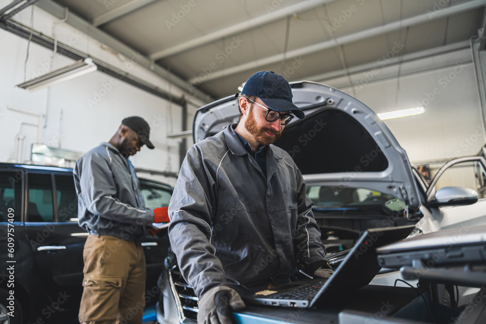 Servicemen making car diagnostics with laptop in a workshop. High quality photo Servicemen making car diagnostics with laptop in a workshop. High quality photo