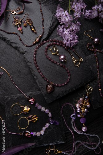 author collection jewelry with lilac gemstones, crystals and pearls demonstrated at black stones background. fashion and jewelry concept. flat lay