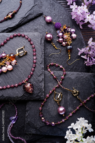 author collection jewelry with lilac gemstones, crystals demonstrated at black stones background. fashion and jewelry concept. flat lay.
